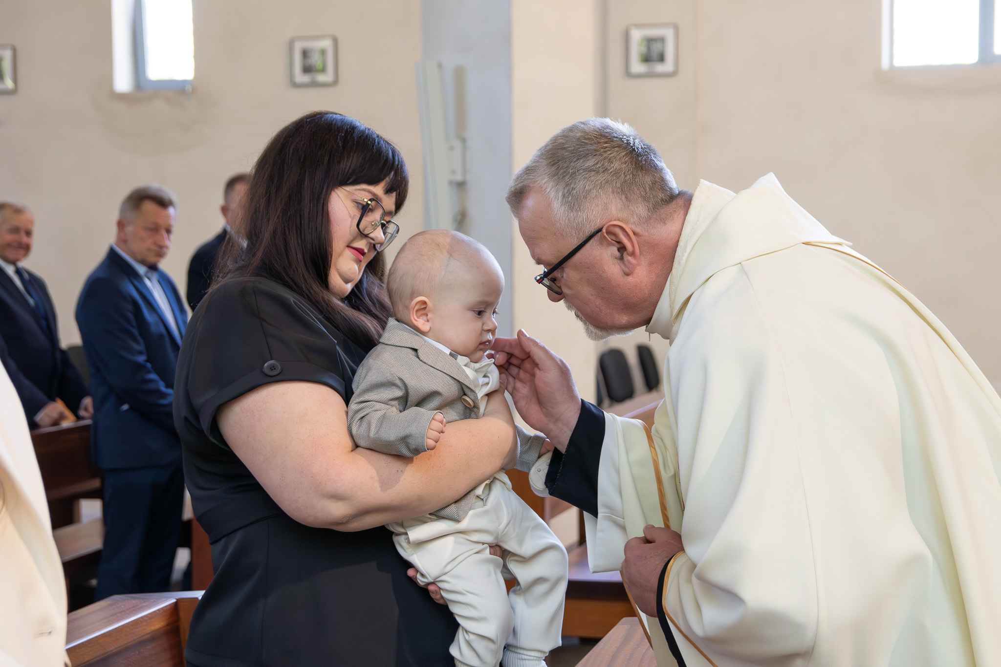 mama trzyma dziecko które zagaduje ksiądz