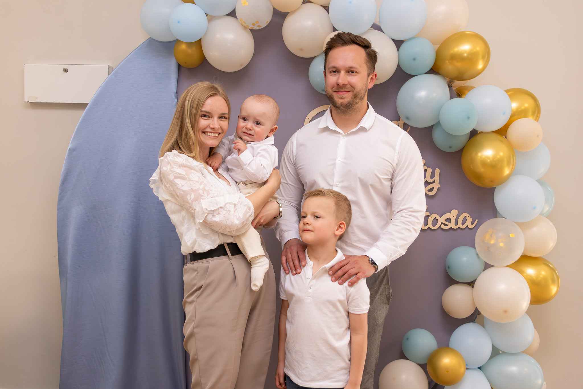 trzy osoby pozują z dzieckiem - uśmiechają się do niego