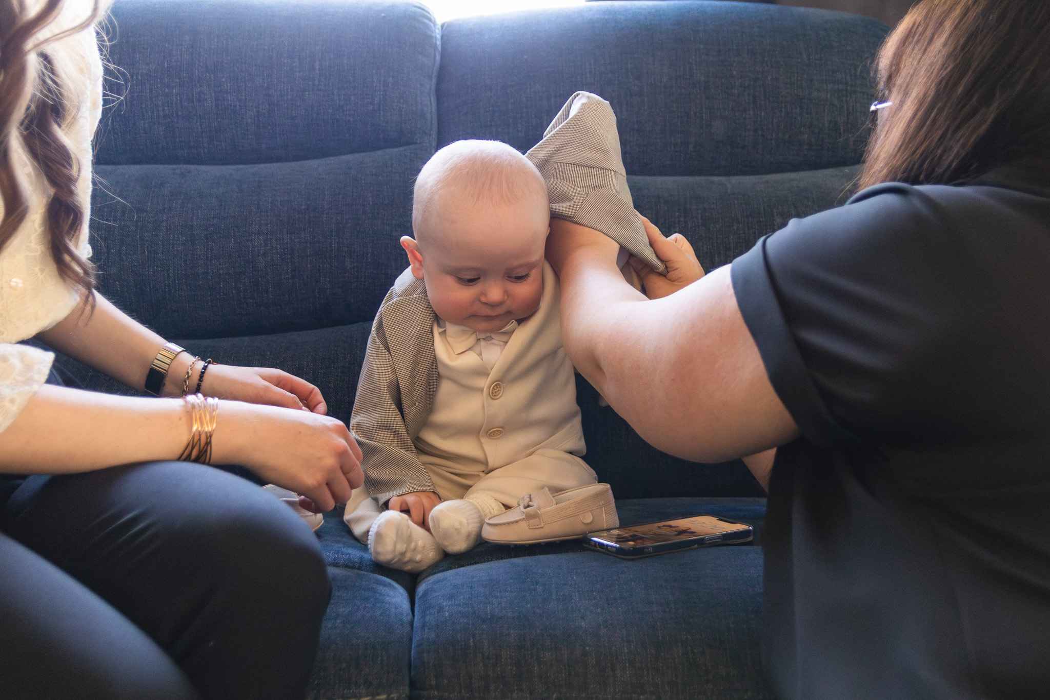 mama i chrzestna zakładają marynarkę dziecku