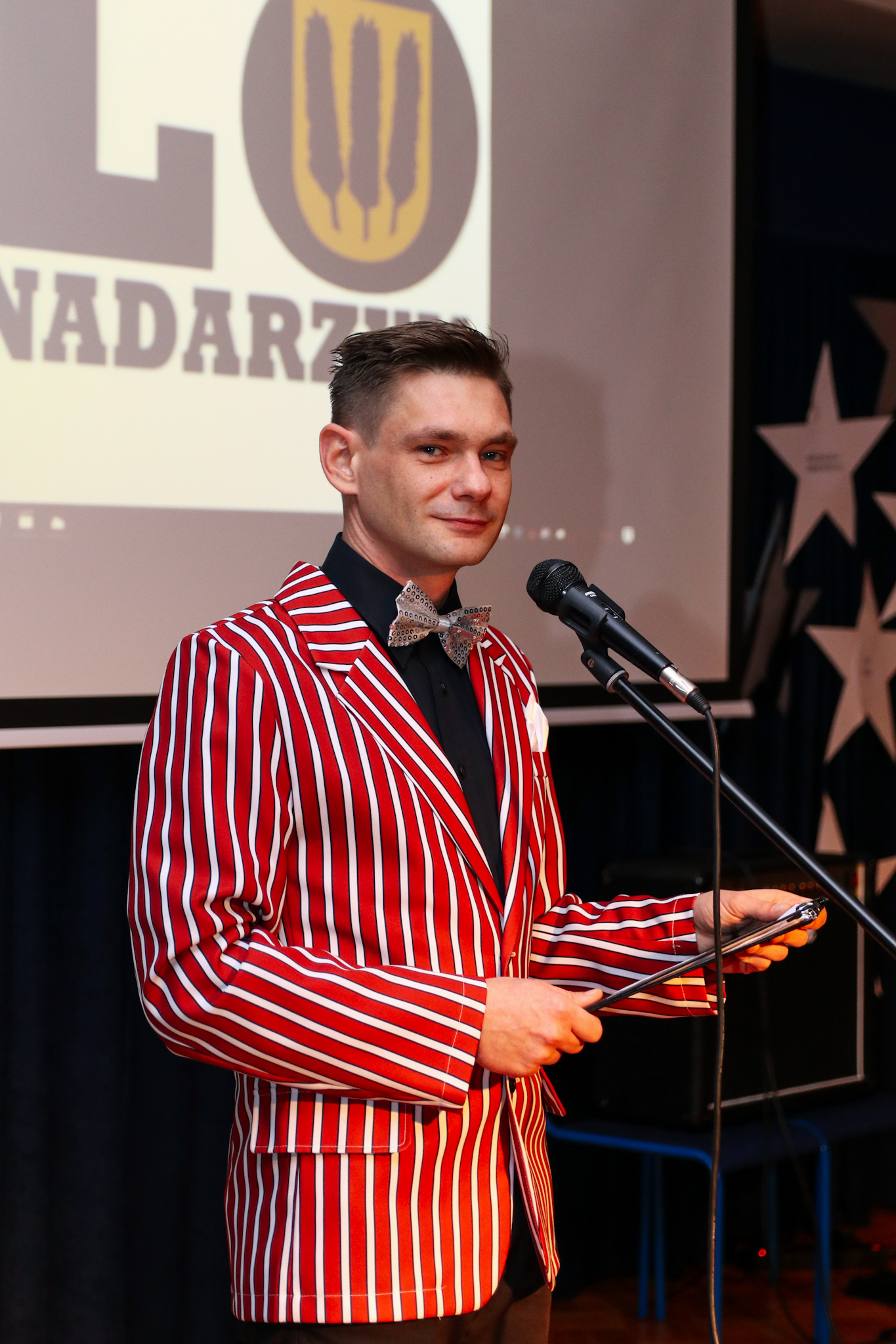 Prezenter LO Nadarzyn w czerwonej marynarce w paski
